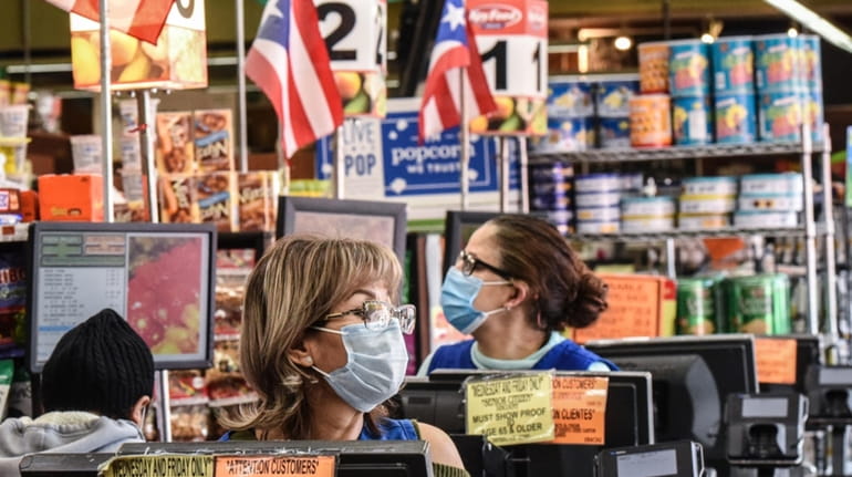 Cashiers wearing protective masks in a grocery store in Brooklyn.