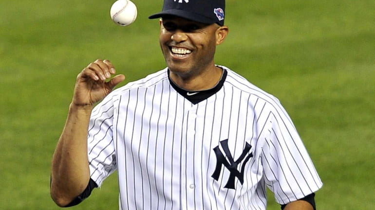 Mariano Rivera playfully flips the ball after throwing out the...