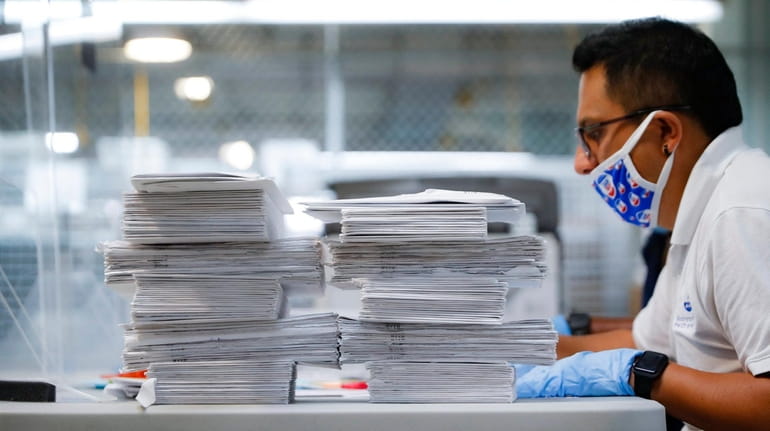 Stacks of ballots are prepared to be checked by a...