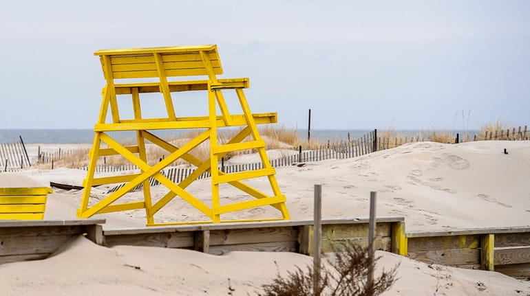 A lifeguard's chair sits away from the water's edge on...