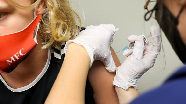 A flu shot is administered by registered nurse Wendy Gonzalez...