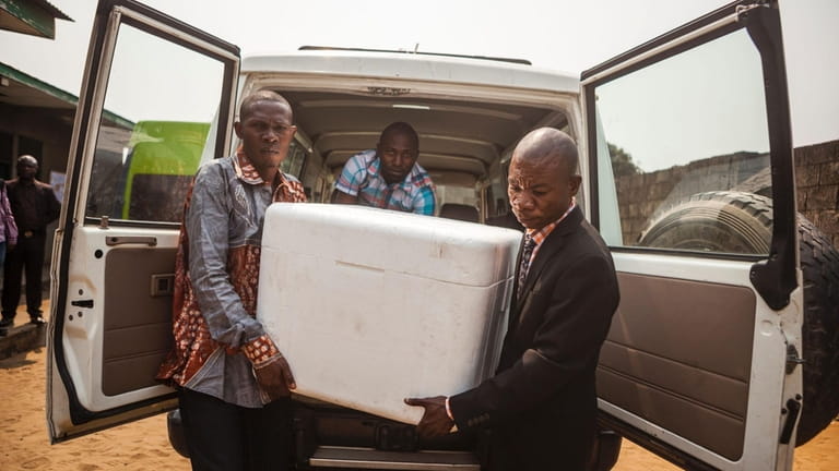 Public employees unload boxes containing yellow fever vaccines in Kinshasa,...
