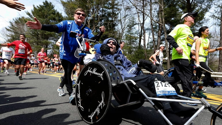 Rick Hoyt, center, is pushed by his father Dick, left,...