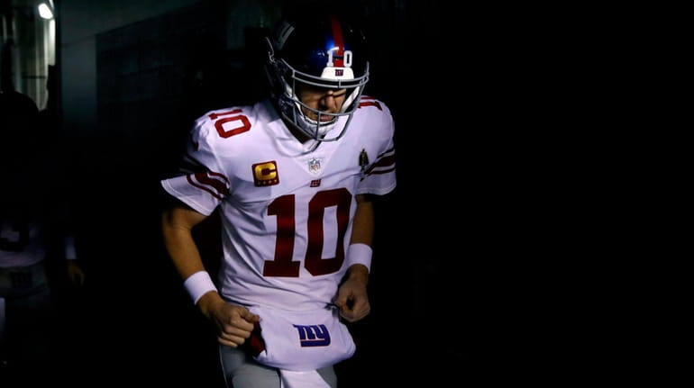 The Giants' Eli Manning runs onto the field before an...