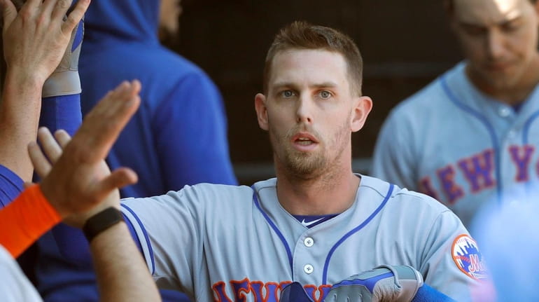 Mets' Jeff McNeil, right, celebrates in the dugout after scoring...