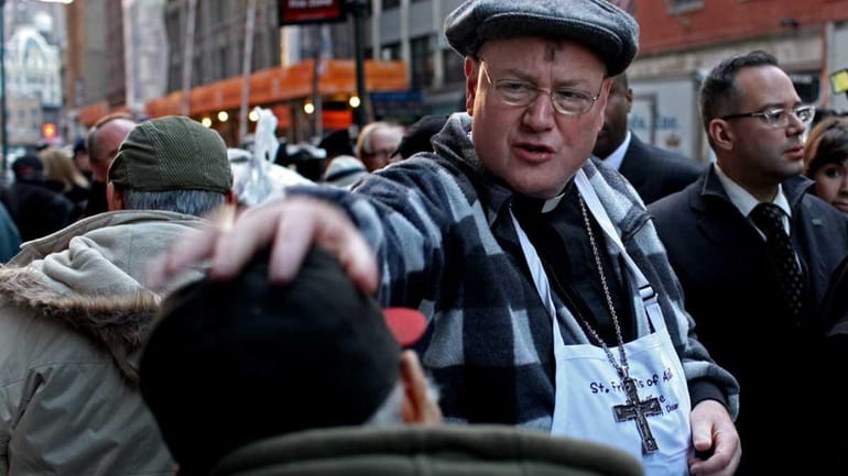 Cardinal Timothy Dolan speaks to a man who just received...