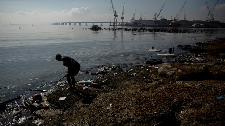 A person digs through the garbage on the banks of...
