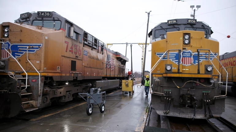 A Union Pacific worker walks between two locomotives that are...
