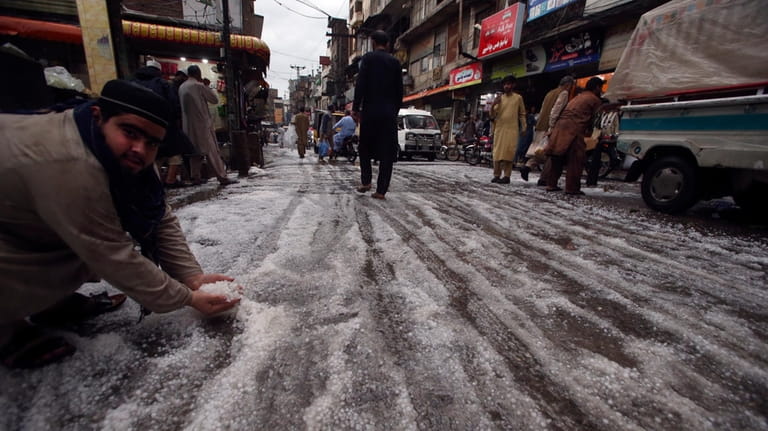 A man holds hailstones after heavy hailstones rain in Peshawar,...