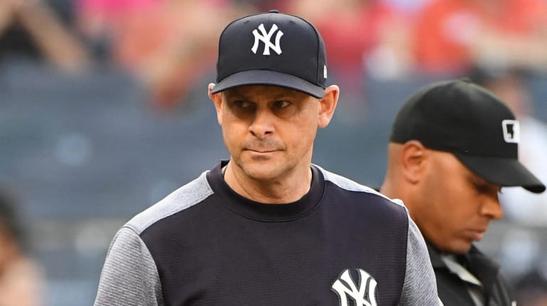 Yankees manager Aaron Boone walks to the dugout after exchanging...
