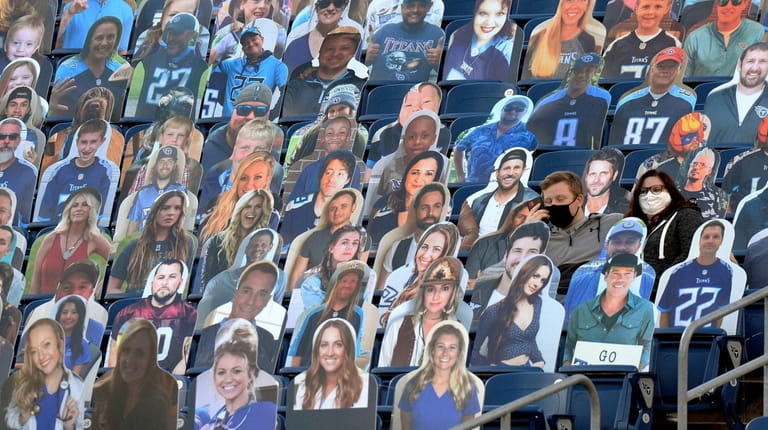 Two spectators sit among a group of cardboard cutouts before an...