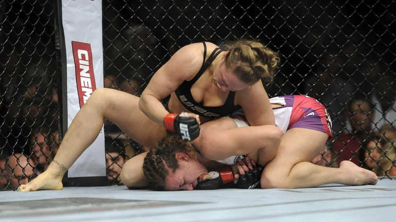 Ronda Rousey, top, punches Miesha Tate during the UFC 168...