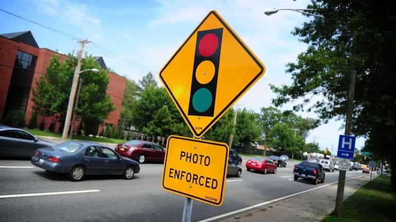 Traffic moves past the sign for the red-light camera on...