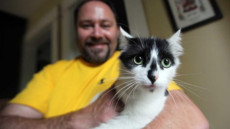 Kevin Vallas holds his cat Jinxy at his home in...
