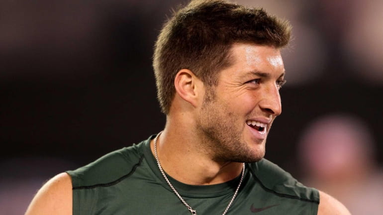 Tim Tebow looks on as he warms up before a...