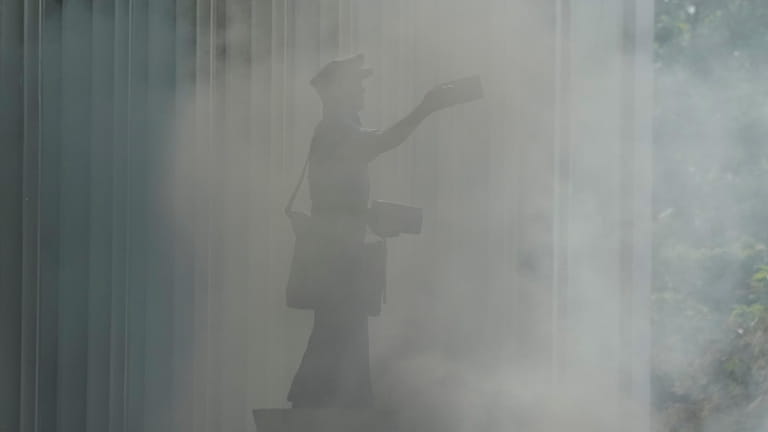 A statue of a postman is enveloped in smoke in...