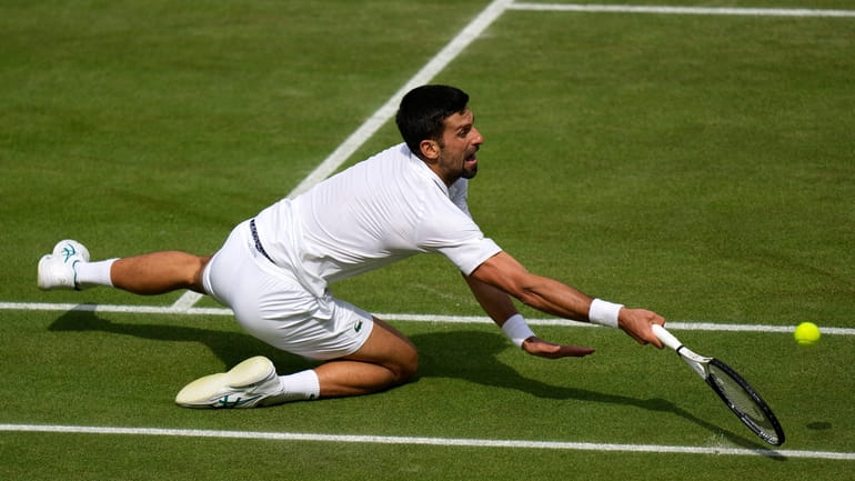 Serbia's Novak Djokovic falls as he returns to Spain's Carlos...