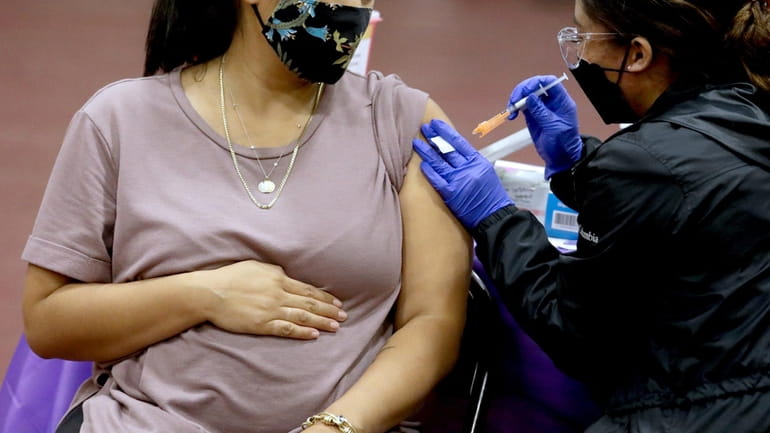 A pregnant woman receives a Pfizer booster shot for COVID-19 on Nov....