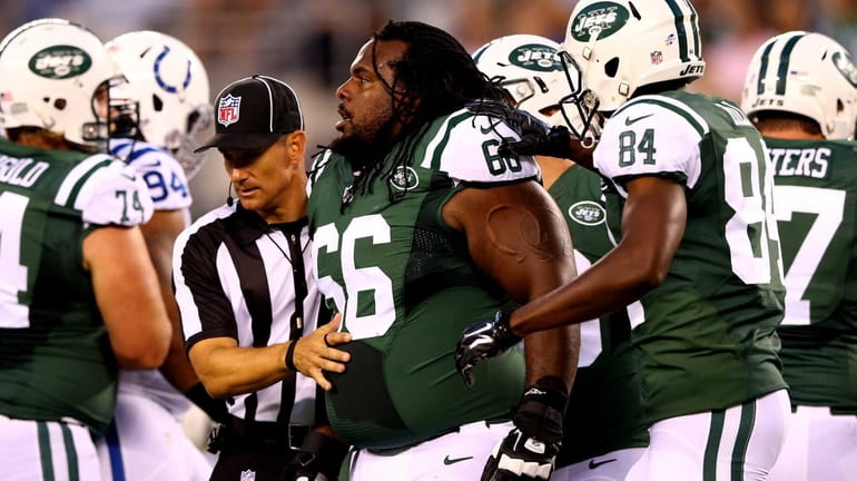 Jets guard Willie Colon reacts after losing his helmet against...
