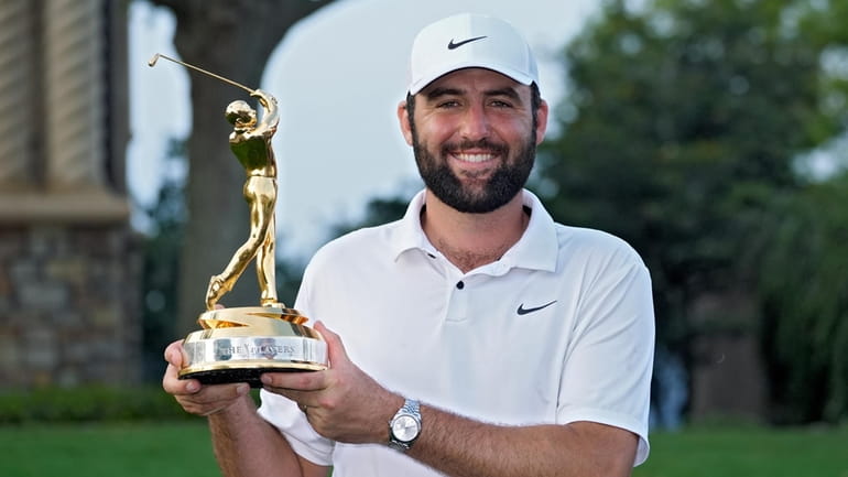 Scottie Scheffler holds the trophy after winning The Players Championship...