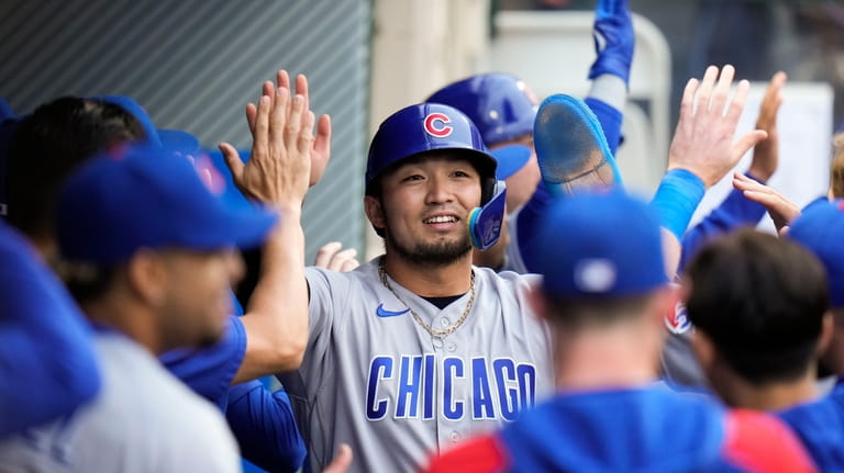 Chicago Cubs' Seiya Suzuki, center, is greeted by teammates after...