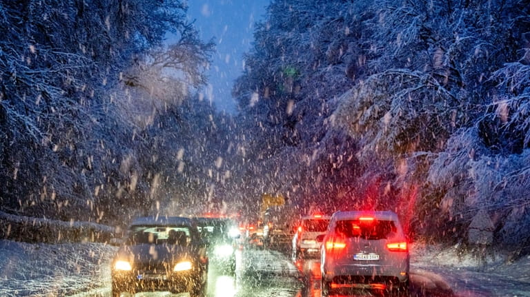 Commuters queue in heavy snowfalls on a country road in...