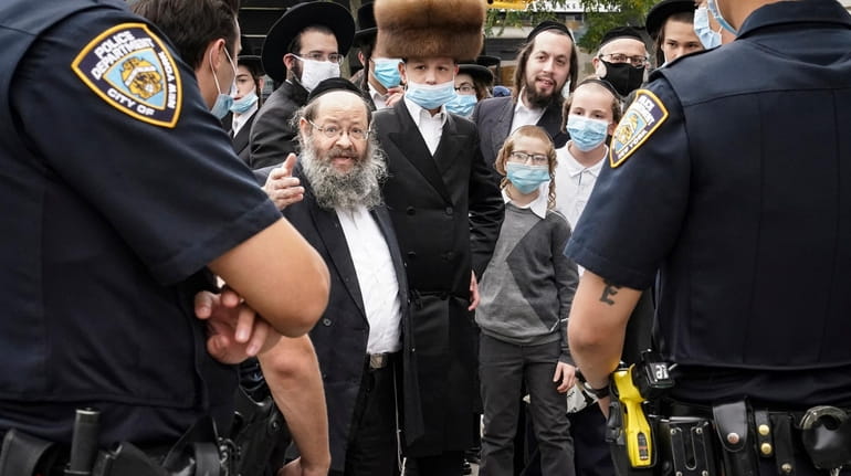Jewish Orthodox community members speak with NYPD officers on Wednesday...