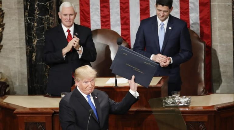 President Donald Trump holds up copies of his speech before...
