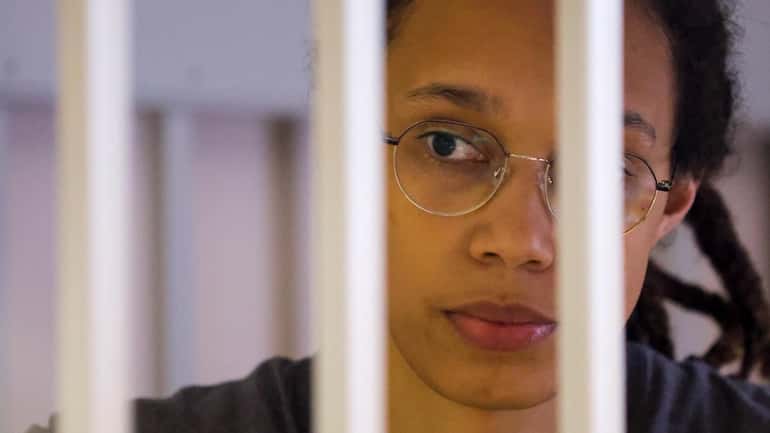WNBA star Brittney Griner listens through bars to the guilty...