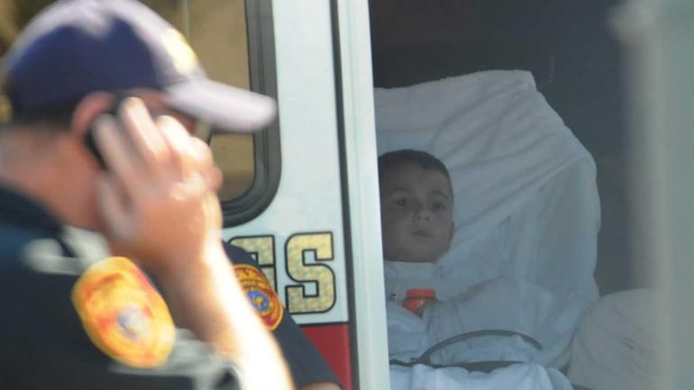 A 5-year-old child rests in an ambulance near the boat...