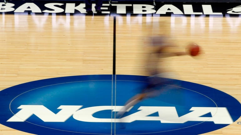 A player runs across the NCAA logo during practice in...