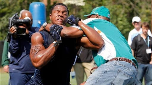 Quinton Coples, left, muscles his way around Miami Dolphin assistant...