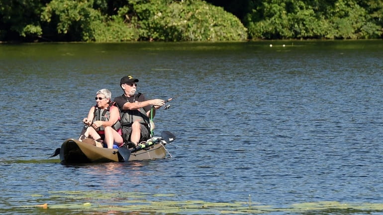 A couple enjoys fishing on a kayak on Yaphank Lake...