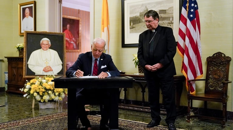 President Joe Biden signs a condolence book at the Apostolic...