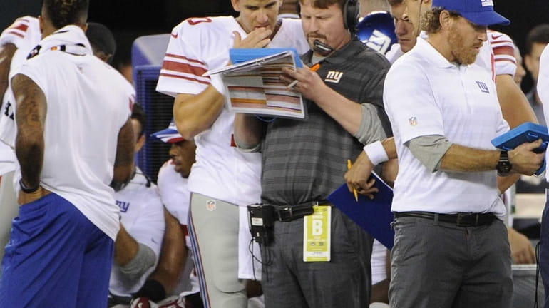 Giants quarterback Eli Manning talks with offensive coordinator Ben McAdoo...