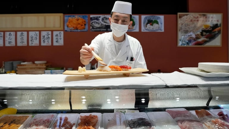 A sushi chef prepares a plate at the Toyosu Market...