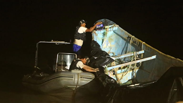 Police help move a boat carrying decomposing corpses to the...