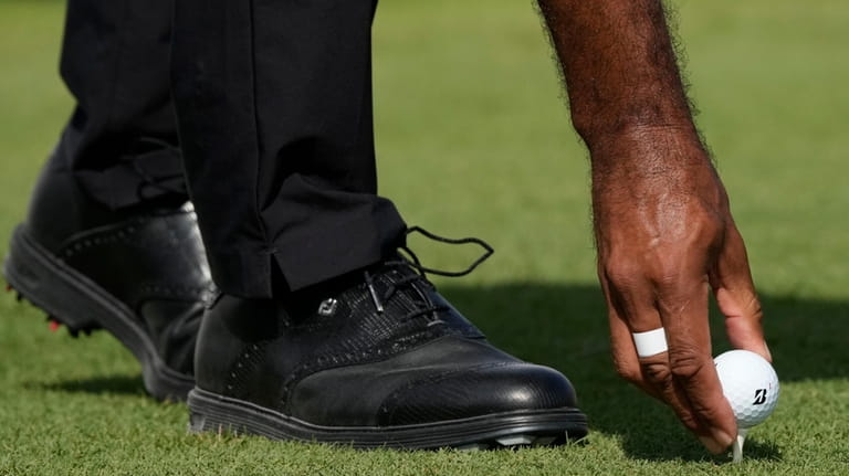 Tiger Woods places his ball on the first tee during...