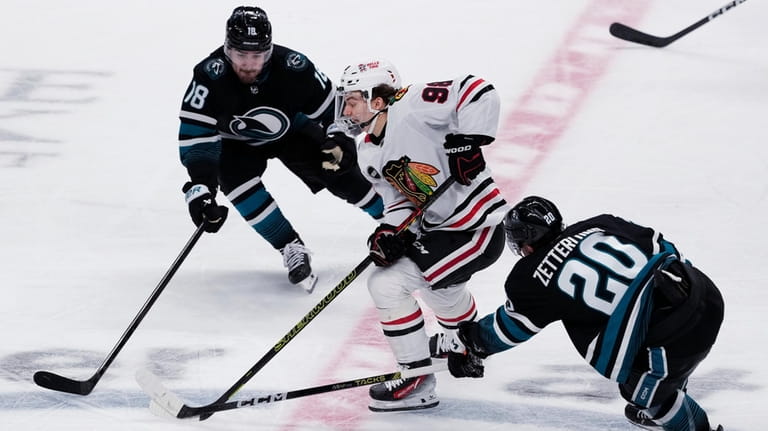 Chicago Blackhawks center Connor Bedard, middle, skates with the puck...
