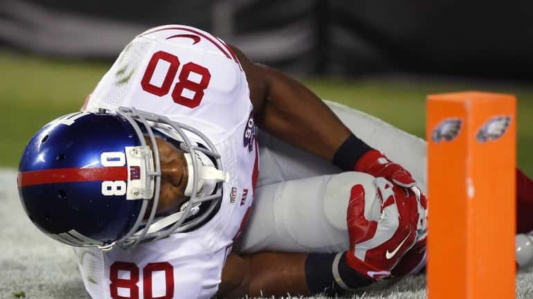 Giants wide receiver Victor Cruz holds his knee after going...