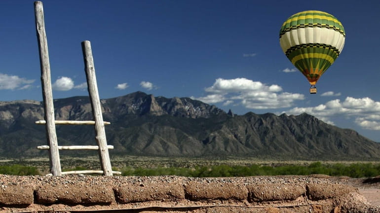 Adobe wall, balloon and the Sandia Mountains in Albuquerque, New...