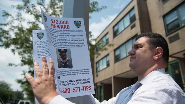 A member of the NYPD places a reward poster on...