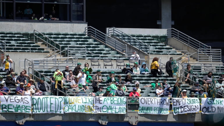 Fans watch from behind signs hanging in right field during...