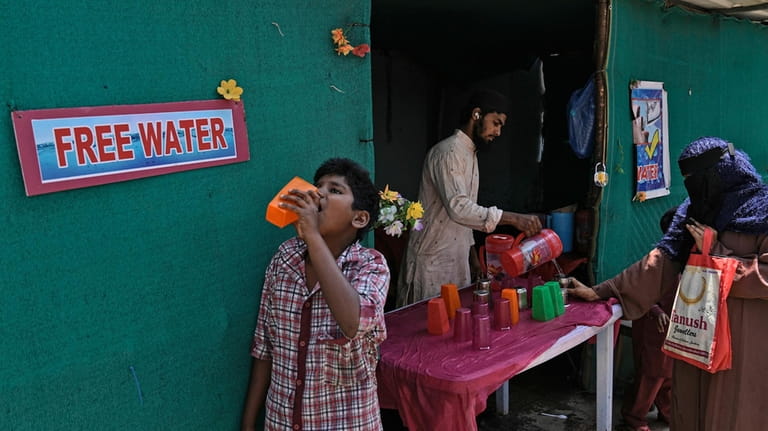 File - A volunteer distributes drinking water next to a...
