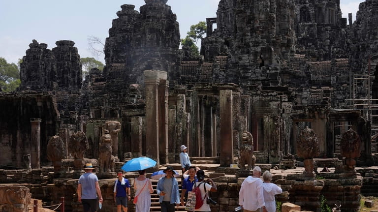 Tourists visit Bayon temple at Angkor Wat temple complex in...