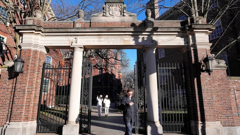 A passer-by walks through a gate to the Harvard University...