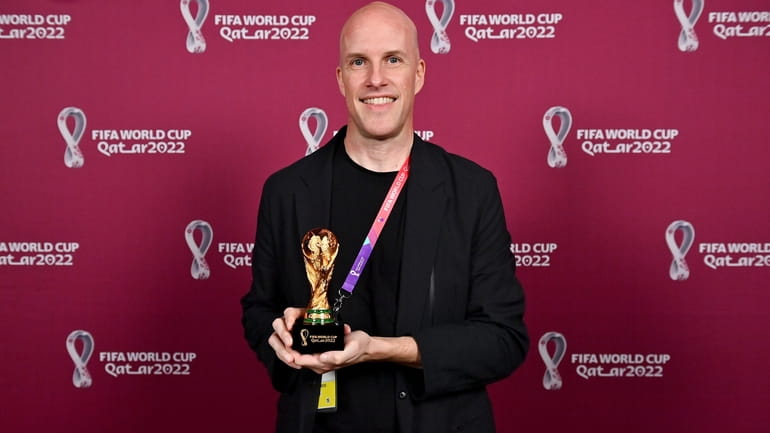 Grant Wahl smiles as he holds a World Cup replica...