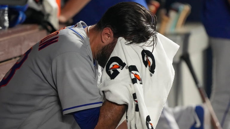 David Peterson of the Mets wipes his face on the bench...