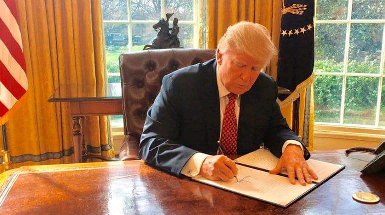 President Donald Trump signs a new executive order Monday, March...