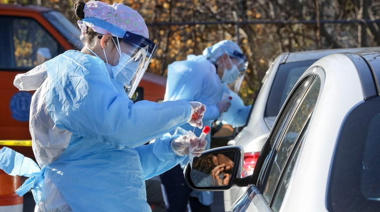 Medical personnel administer COVID-19 swab tests last month at a drive-thru...